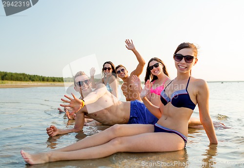 Image of smiling friends in sunglasses on summer beach