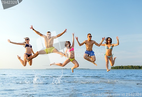 Image of smiling friends in sunglasses on summer beach