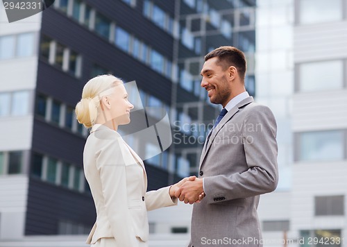 Image of smiling businessmen standing over office building