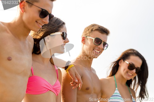 Image of smiling friends in sunglasses on summer beach