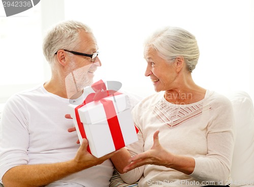 Image of happy senior couple with gift box at home