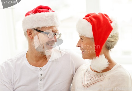 Image of happy senior couple in santa helper hats at home