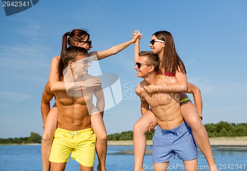 Image of smiling friends in sunglasses on summer beach