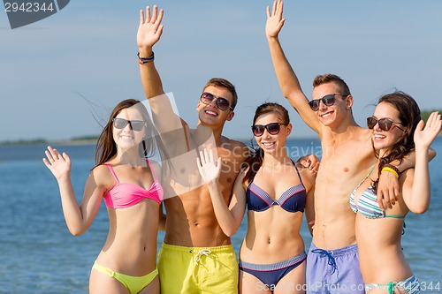 Image of smiling friends in sunglasses on summer beach