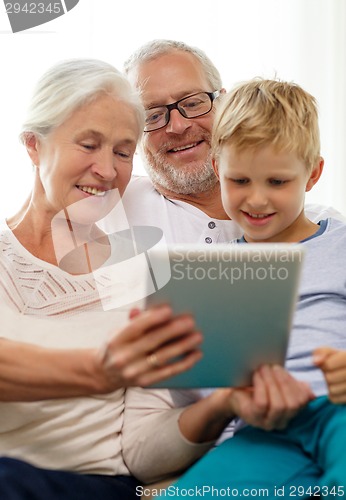 Image of smiling family with tablet pc at home