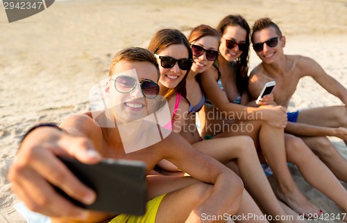 Image of friends with smartphones on beach