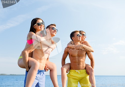 Image of smiling friends in sunglasses on summer beach