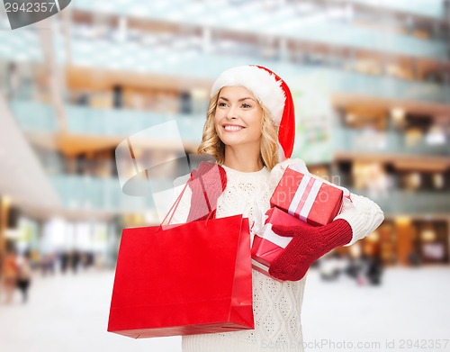 Image of smiling young woman in santa helper hat with gifts