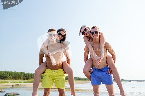 Image of smiling friends in sunglasses on summer beach