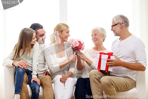 Image of happy family with bunch and gift box at home