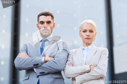 Image of serious businessmen standing over office building