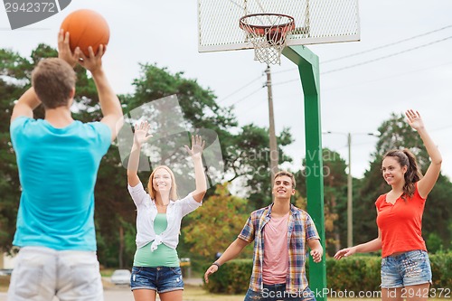 Image of group of smiling teenagers playing basketball