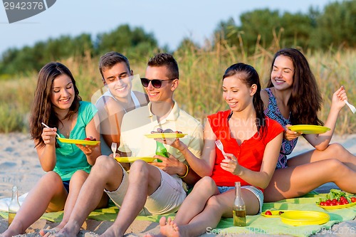 Image of smiling friends sitting on summer beach