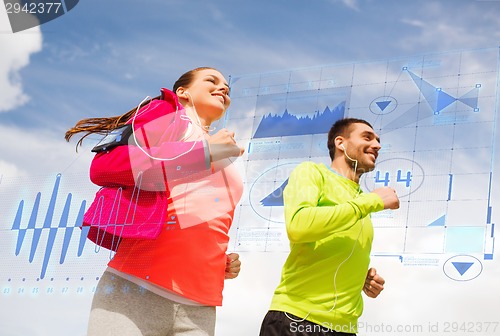 Image of smiling couple with earphones running outdoors