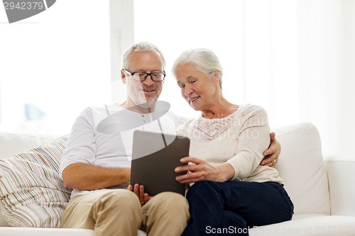 Image of happy senior couple with tablet pc at home