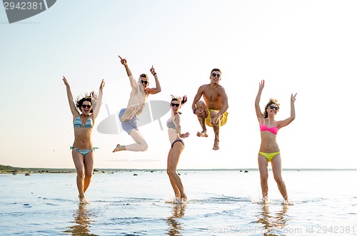 Image of smiling friends in sunglasses on summer beach