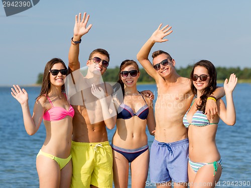 Image of smiling friends in sunglasses on summer beach