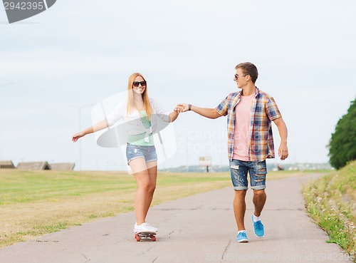 Image of smiling couple with skateboard outdoors