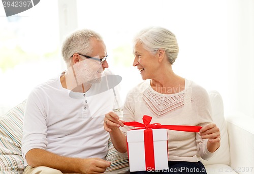 Image of happy senior couple with gift box at home
