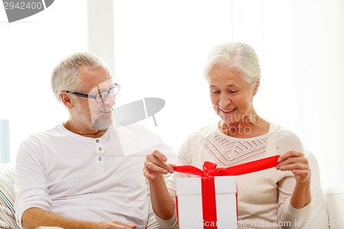 Image of happy senior couple with gift box at home