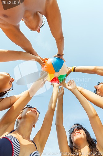 Image of smiling friends in circle on summer beach
