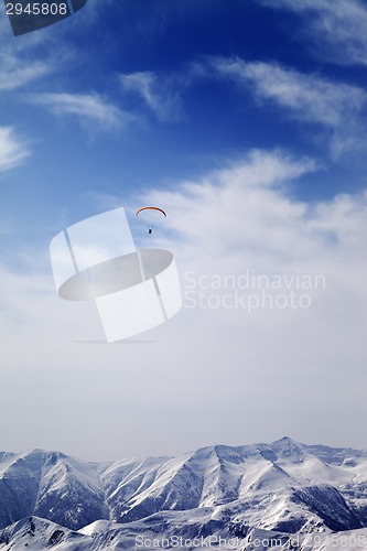 Image of Sunlight mountain with clouds and silhouette of paraglider