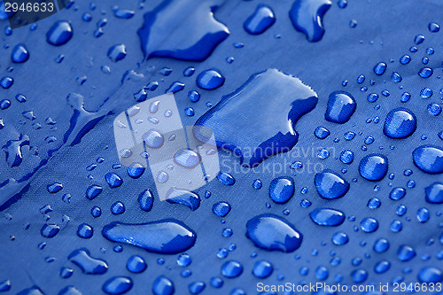 Image of Closeup of rain drops on a blue umbrella