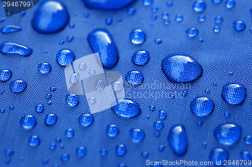 Image of Closeup of rain drops on a blue umbrella