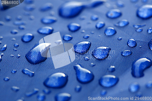 Image of Closeup of rain drops on a blue umbrella