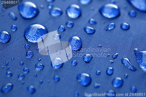 Image of Closeup of rain drops on a blue umbrella