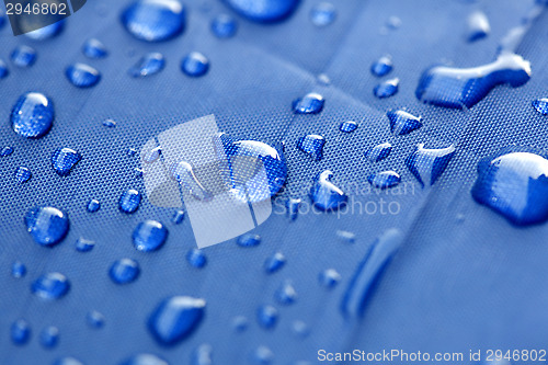 Image of Closeup of rain drops on a blue umbrella