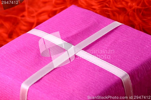Image of gift box with white ribbon on red background
