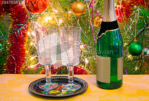 Image of Christmas holiday, wine and glasses near a Christmas fir-tree.