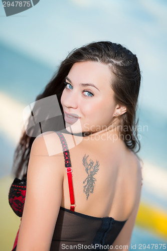 Image of Portrait of smiling young brunette with tattoo