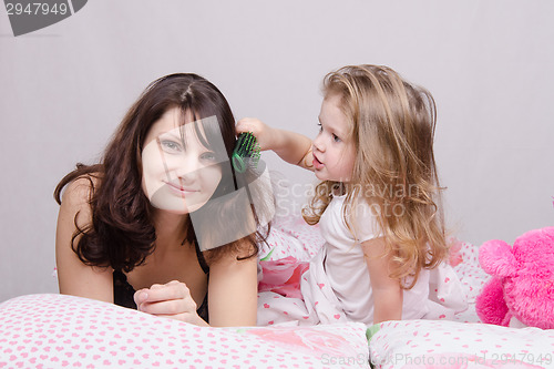 Image of Girl combing her hair with enthusiasm mum