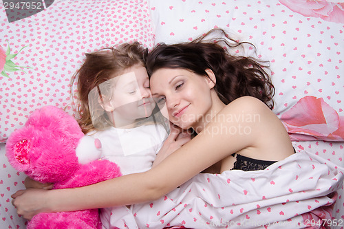 Image of Mom and daughter happily resting in bed