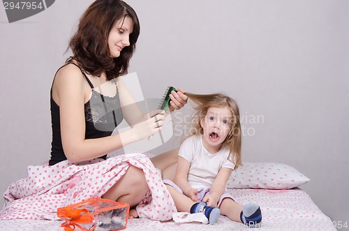 Image of Mom combing hair-year old daughter