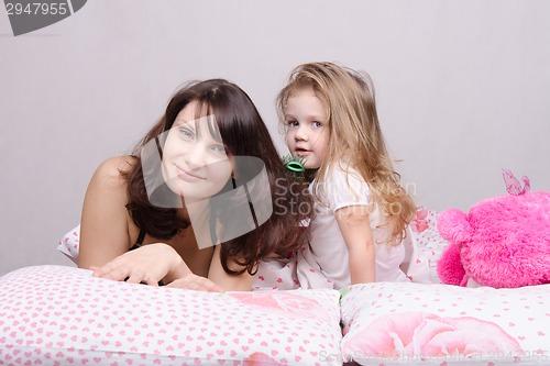 Image of Mom and daughter with a hairbrush in her bed