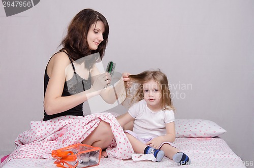 Image of Mom combing her daughter in the morning