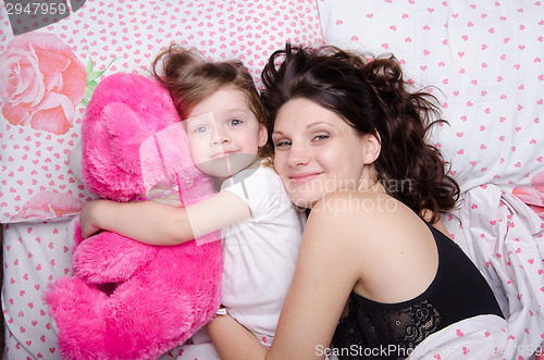 Image of Mom hugs her daughter lying in bed