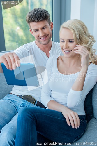 Image of Couple smiling and laughing as they read a tablet