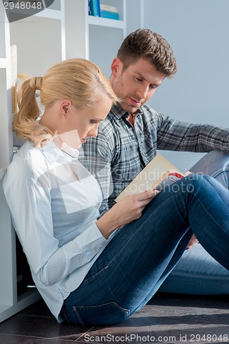 Image of Young Couple Sitting on Floor Reading Book
