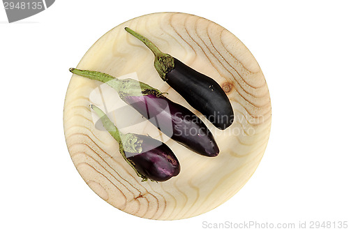 Image of three eggplant on a round wooden plate