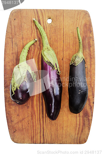Image of three eggplant on a wooden cutting board