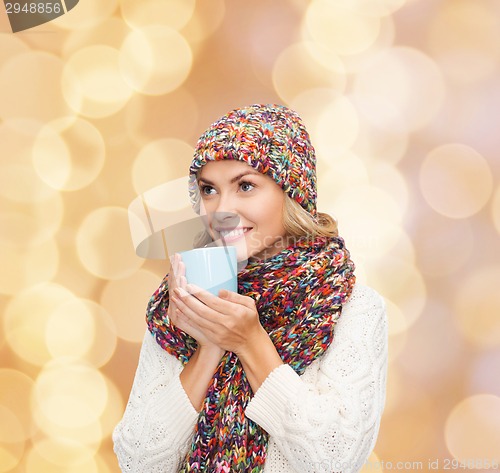 Image of smiling young woman in winter clothes with cup