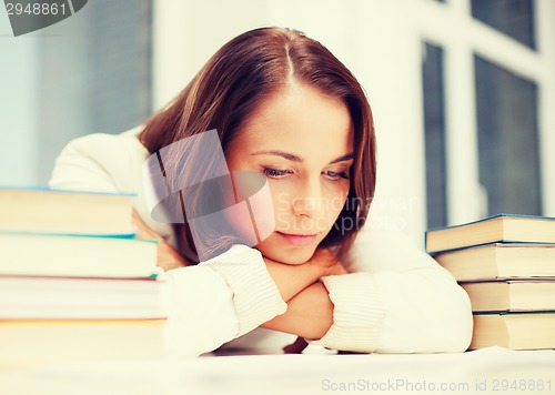 Image of bored young woman with many books indoors