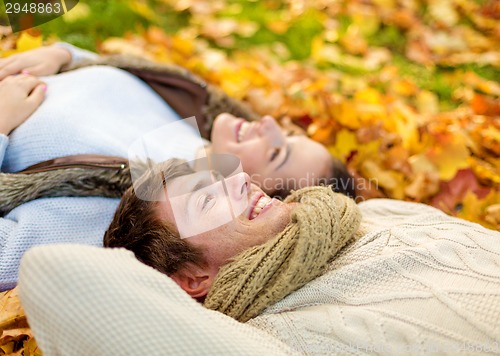 Image of close up of smiling couple lying in autumn park