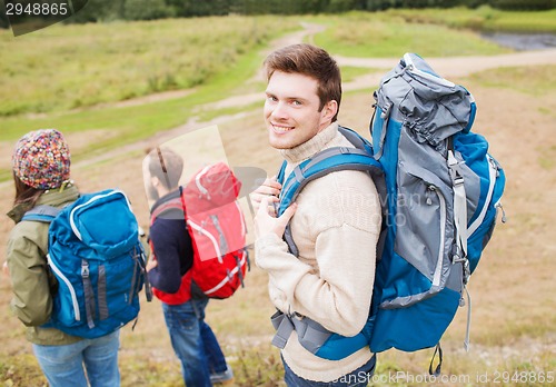 Image of group of smiling friends with backpacks hiking