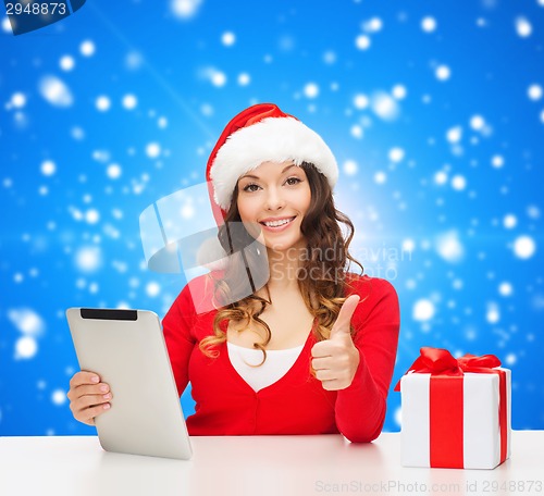Image of smiling woman in santa hat with gift and tablet pc