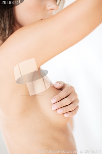 Image of woman checking breast for signs of cancer